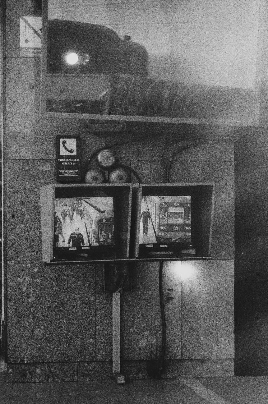 grayscale photo of screens with images of trains and people in a train station